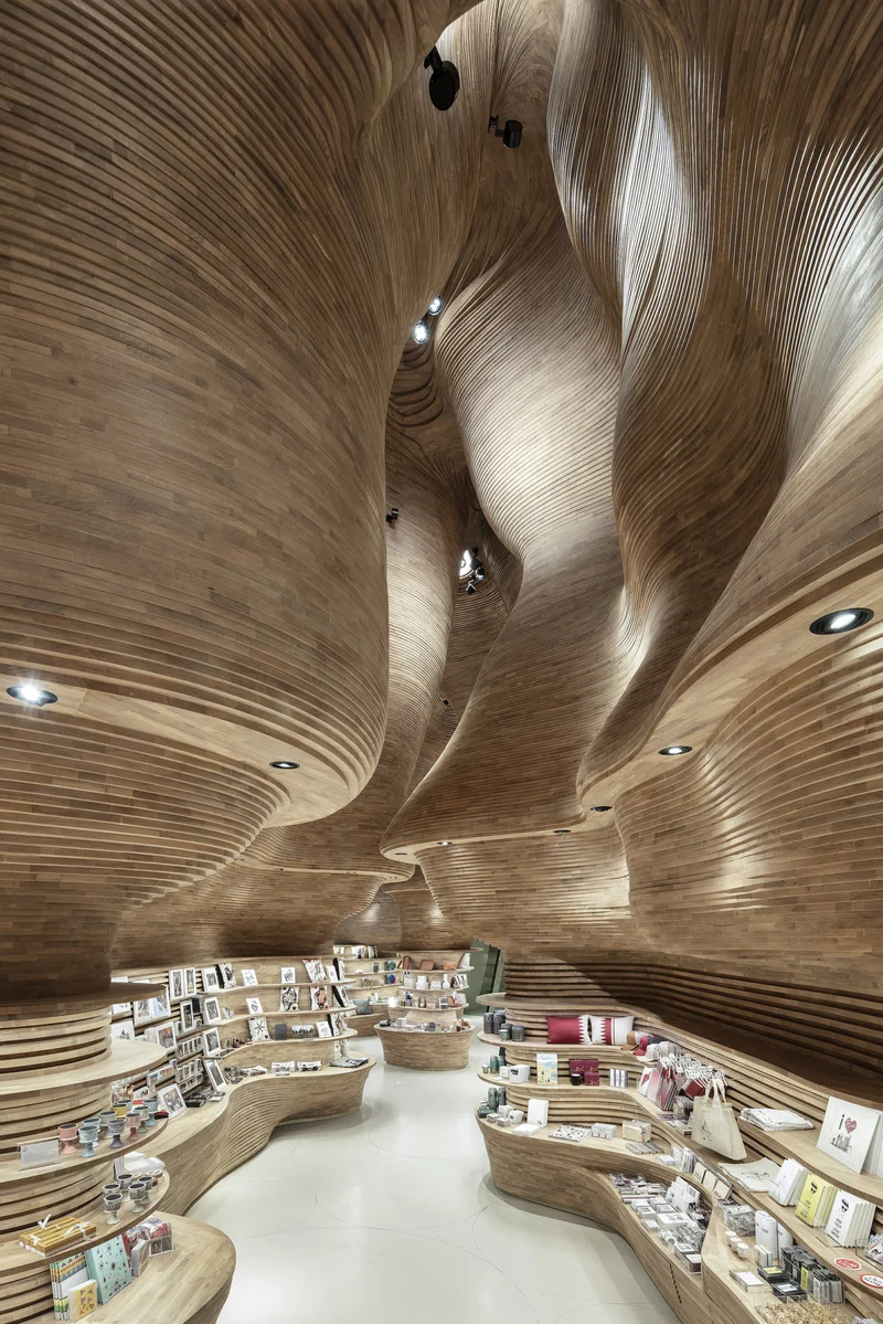 Interior cenográfico orgânico em madeira esculpida — exemplo de espaço de varejo com forte hierarquia visual e narrativa espacial