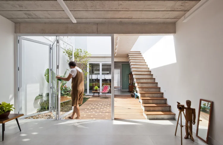 Casa contemporânea brasileira com pátio interno, escada de concreto e integração indoor-outdoor projetada por arquiteto