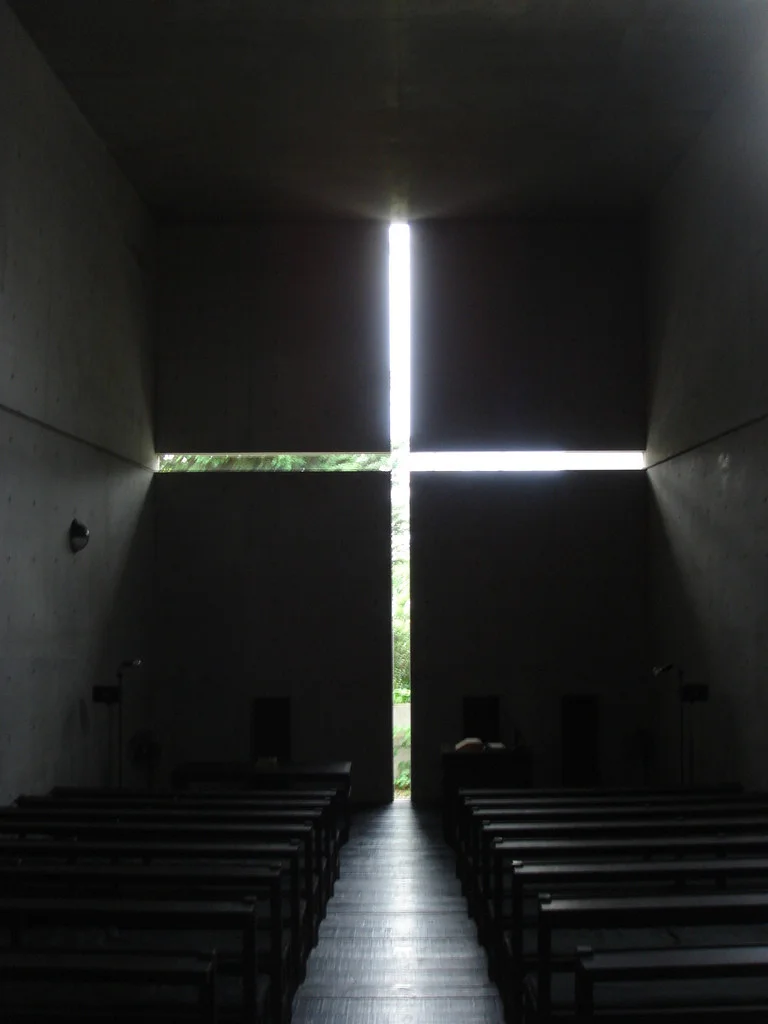 Igreja da Luz de Tadao Ando, com a luz entrando por uma fresta em forma de cruz na parede de concreto.