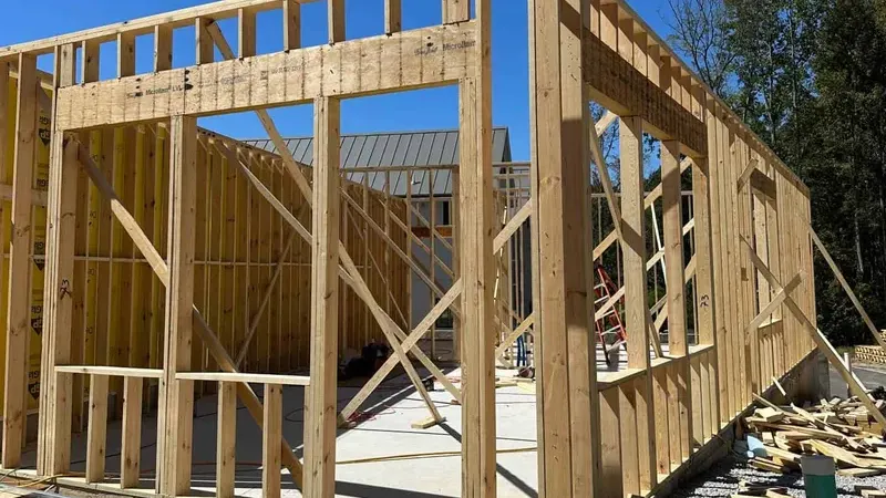 Estrutura de wood-frame em construção — montantes verticais e travessas de pinus tratado formando paredes leves
