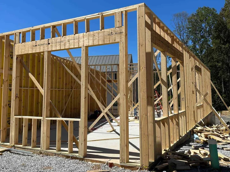 Estrutura de casa em wood-frame com montantes de madeira tratada já posicionados sobre laje de concreto em canteiro brasileiro