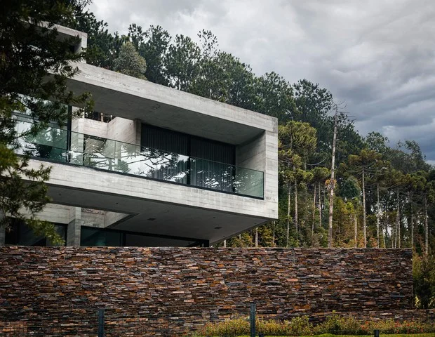 Casa contemporânea em Campos do Jordão, com grandes painéis de vidro e estrutura de madeira.
