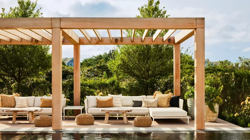 Pergolado de madeira sobre lounge externo com piscina e jardim