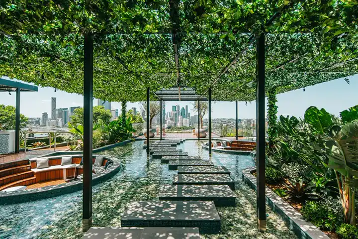 Parque urbano profissional visto de cima com canteiros geométricos, espelho d'água em curva, caminhos pavimentados e árvores em camadas