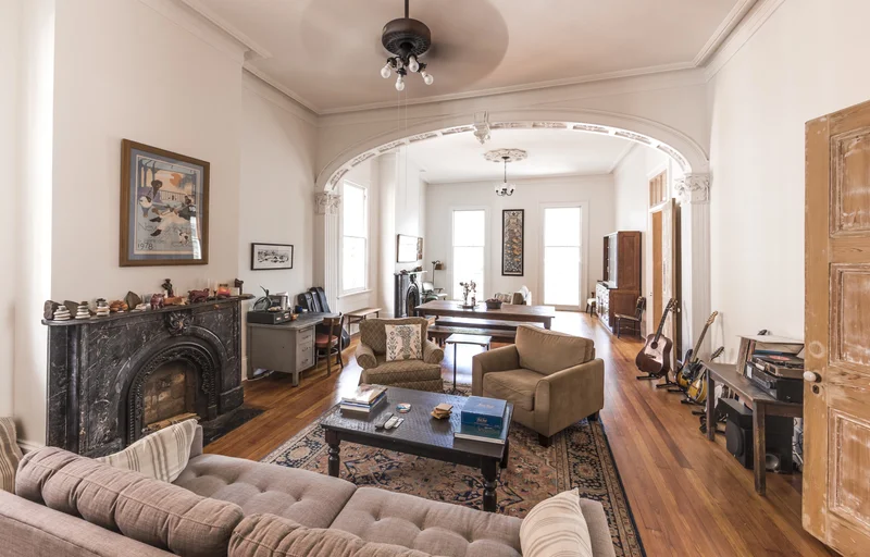 Sala antiga estilo brownstone com pé-direito alto e lustre pendente baixo dominando o ambiente